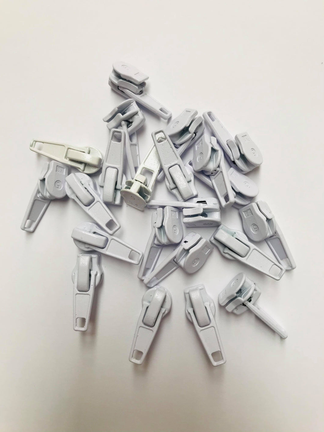 No 5 white plastic-coated metal zip pullers or ‘sliders’ are to suit our continuous zip. 