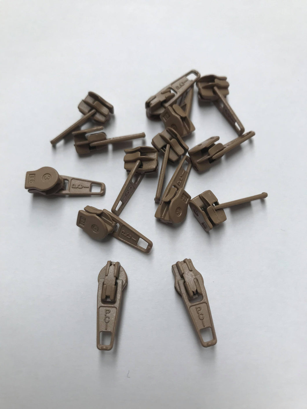 No 5 beige lastic-coated metal zip pullers or ‘sliders’ are to suit our continuous zip. 
